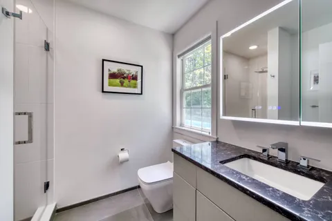 a bathroom with a granite countertop sink mirror and toilet