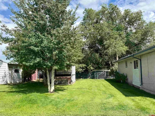 a view of a backyard with table and chairs and a large tree