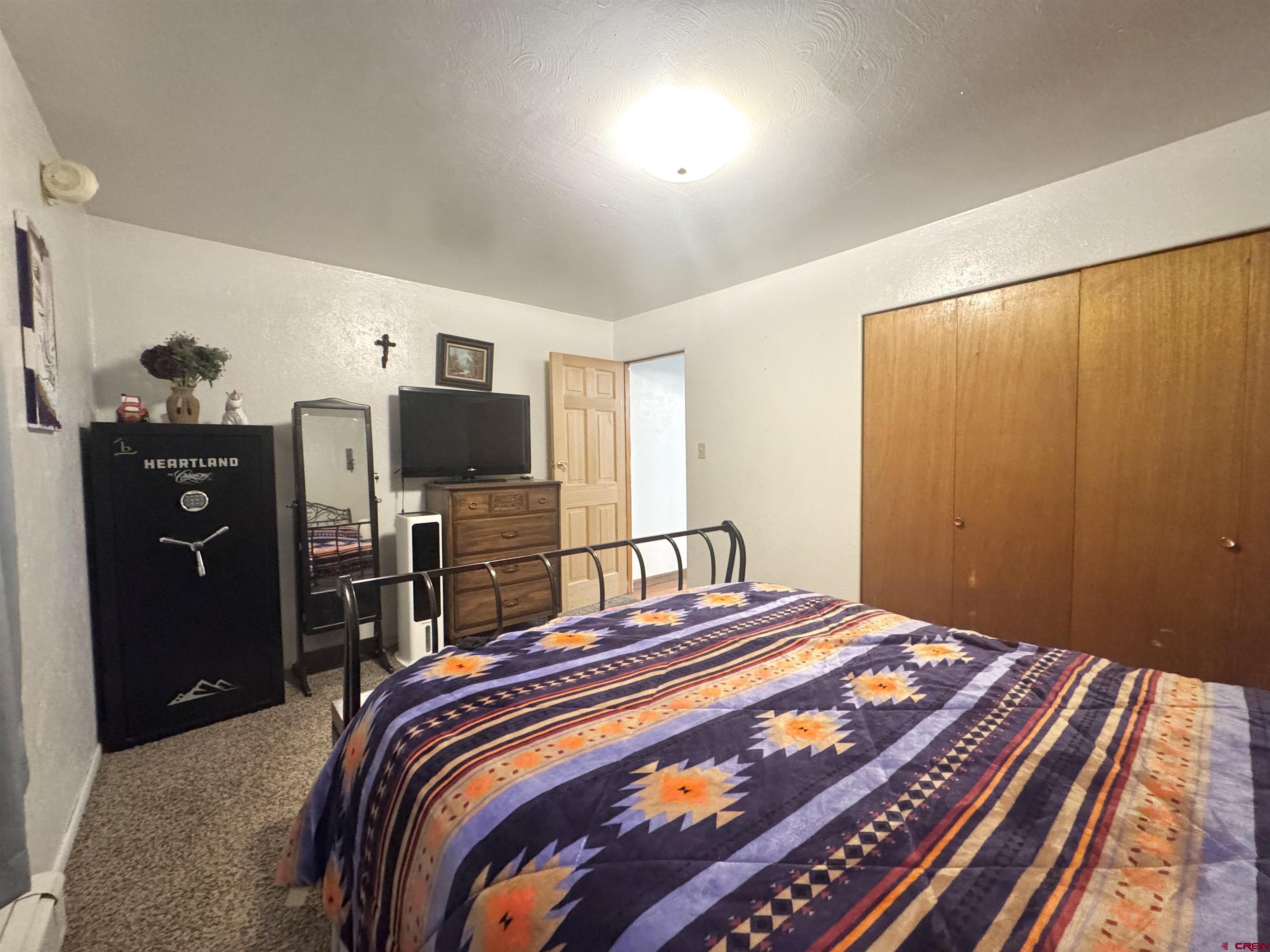 113 Conejos Street Romeo, CO 81148 - Photo 24 of 36 a bedroom with a bed and a flat tv screen on dresser