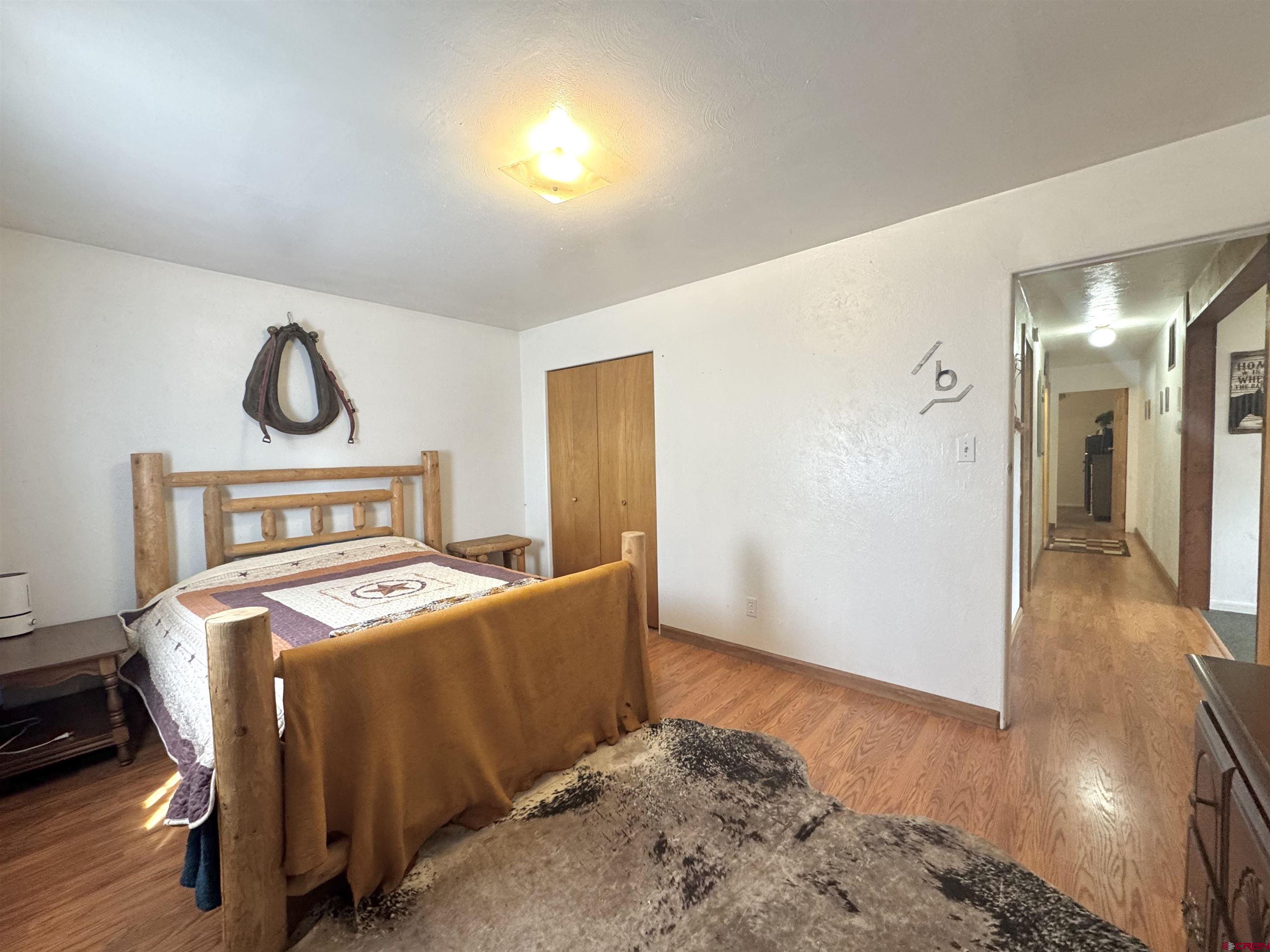 113 Conejos Street Romeo, CO 81148 - Photo 28 of 36 a bedroom with a bed and wooden floor