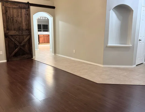 an empty room with wooden floor mirror and windows