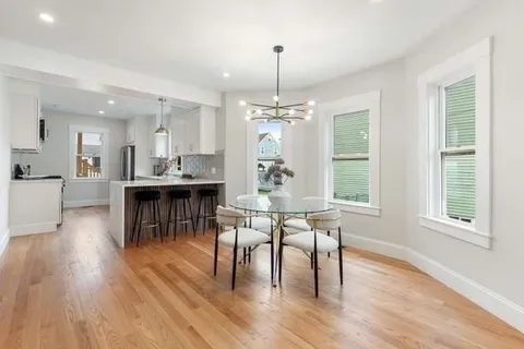 a dining room with wooden floor a chandelier a wooden table and chairs