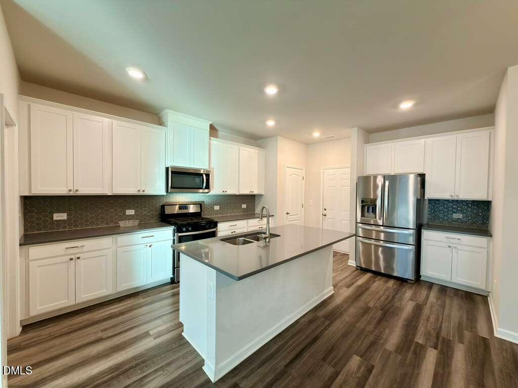 1152 Chestnut Bluff Run Apex, NC 27502 - Photo 12 of 35 a kitchen with a sink a stove a refrigerator and white cabinets