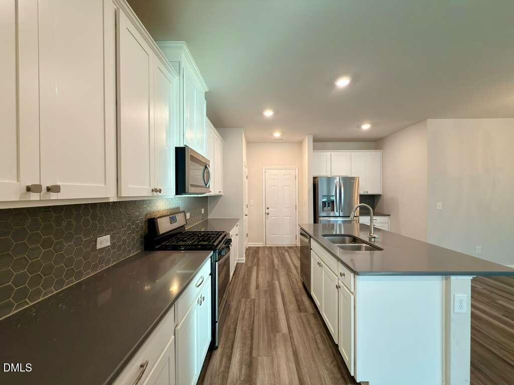 1152 Chestnut Bluff Run Apex, NC 27502 - Photo 13 of 35 a kitchen with stainless steel appliances granite countertop a stove a sink and a microwave