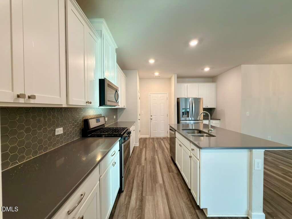 1152 Chestnut Bluff Run Apex, NC 27502 - Photo 14 of 35 a kitchen with stainless steel appliances granite countertop a stove a sink and a refrigerator