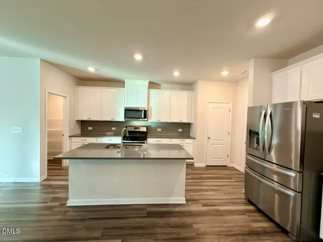 a view of kitchen with stainless steel appliances granite countertop refrigerator stove top oven and cabinets