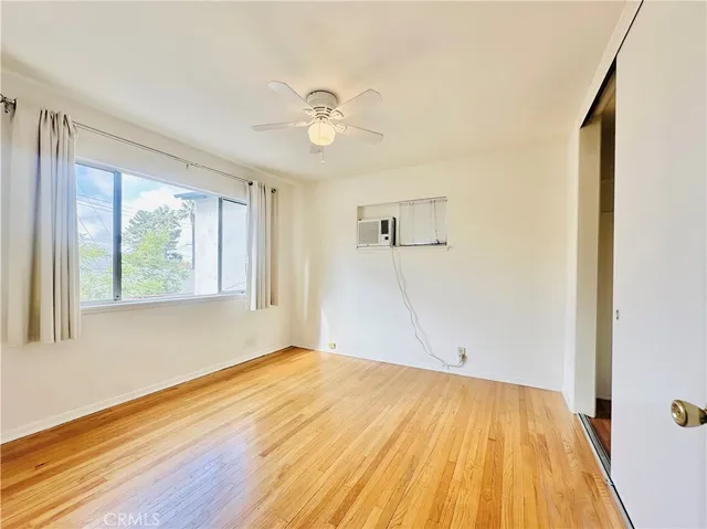 a view of empty room with wooden floor and fan
