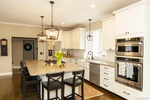 a kitchen with stainless steel appliances kitchen island granite countertop a stove a sink a dining table and chairs with wooden floor