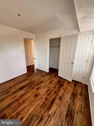 a view of an empty room with wooden floor and stairs