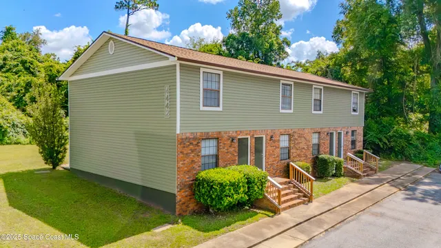 a view of a house with a yard and potted plants