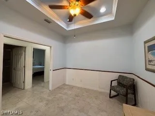 an empty room with chandelier fan and windows