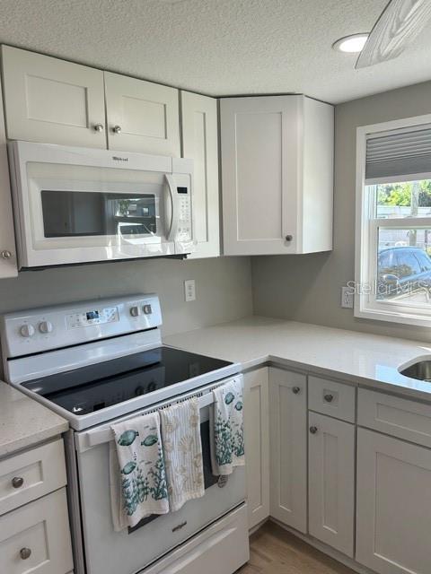 6837 Flicker Lane Hudson, FL 34667 - Photo 3 of 28 a kitchen with stainless steel appliances granite countertop a stove a microwave and white cabinets