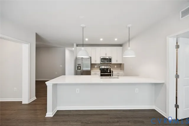 a large white kitchen with kitchen island white cabinetry and wooden floor