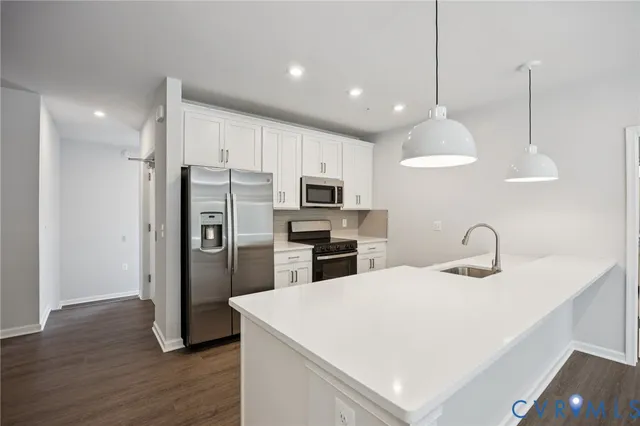 a kitchen with kitchen island stainless steel appliances a sink cabinets and wooden floor