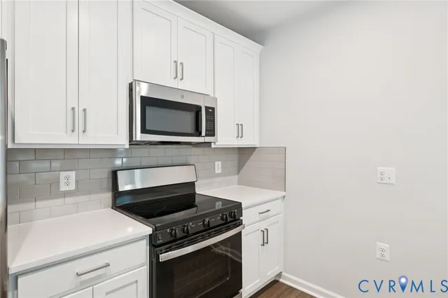 a kitchen with granite countertop white cabinets and stainless steel appliances