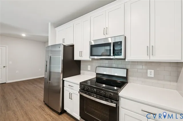 a kitchen with stainless steel appliances white cabinets and a stove top oven