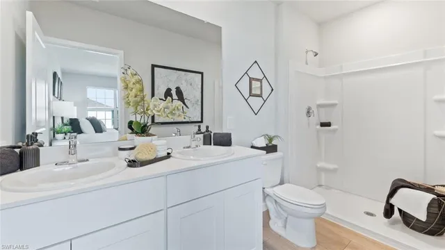 a bathroom with a toilet sink double vanity and mirror