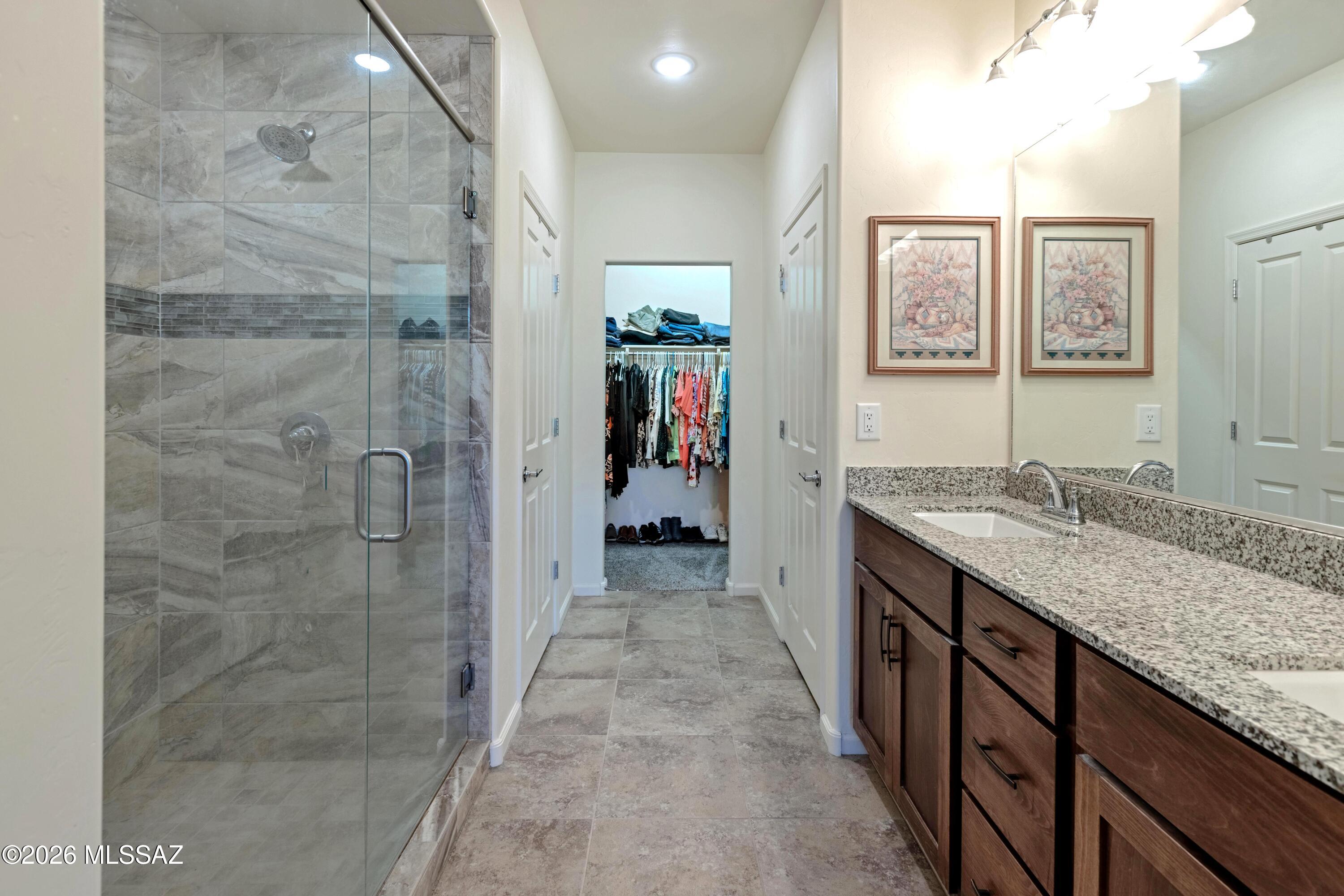 61193 East Shale Road Oracle, AZ 85623 - Photo 18 of 50 a bathroom with a granite countertop sink a mirror a window and a shower