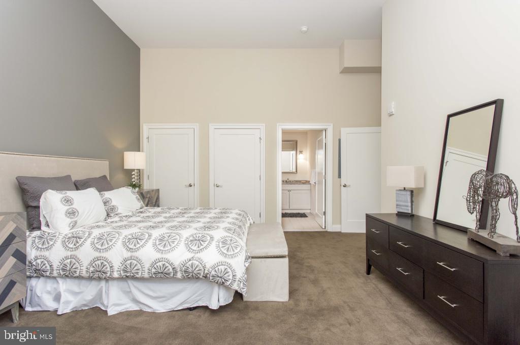 230-38 North 21st Street, Unit 409 Philadelphia, PA 19103 - Photo 6 of 17 a spacious bedroom with a bed and dresser with mirror