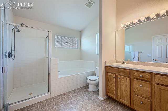 12510 Motley Road Peyton, CO 80831 - Photo 19 of 36 Full bathroom with tile flooring, double vanity, toilet, and plus walk in shower