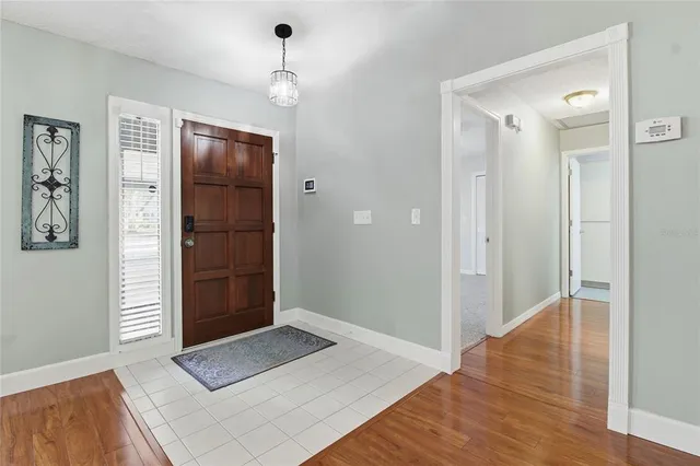 an empty room with wooden floor chandelier and windows