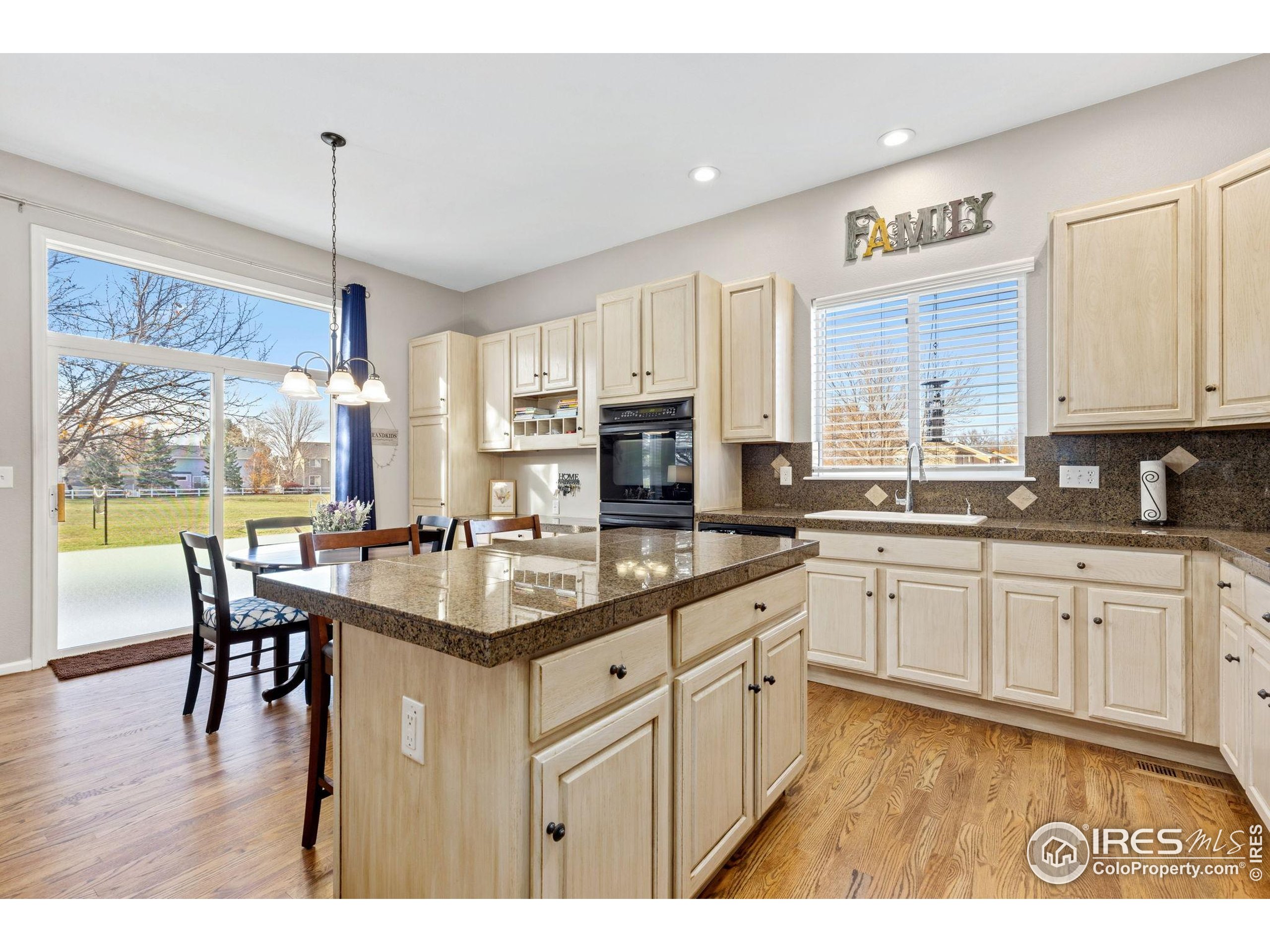 10166 Scenic Court Firestone, CO 80504 - Photo 10 of 33 a kitchen with stainless steel appliances granite countertop a stove a sink dishwasher a dining table and chairs with wooden floor