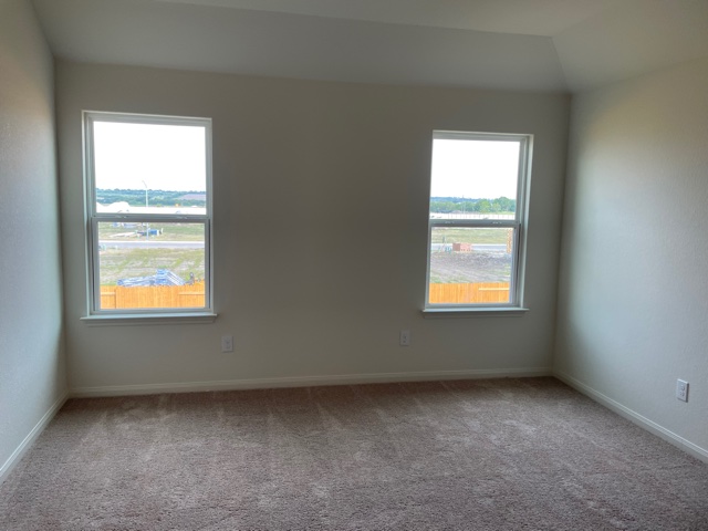 18812 Speculator Lane Elgin, TX 78621 - Photo 15 of 24 Empty room featuring light colored carpet, healthy amount of natural light, and vaulted ceiling