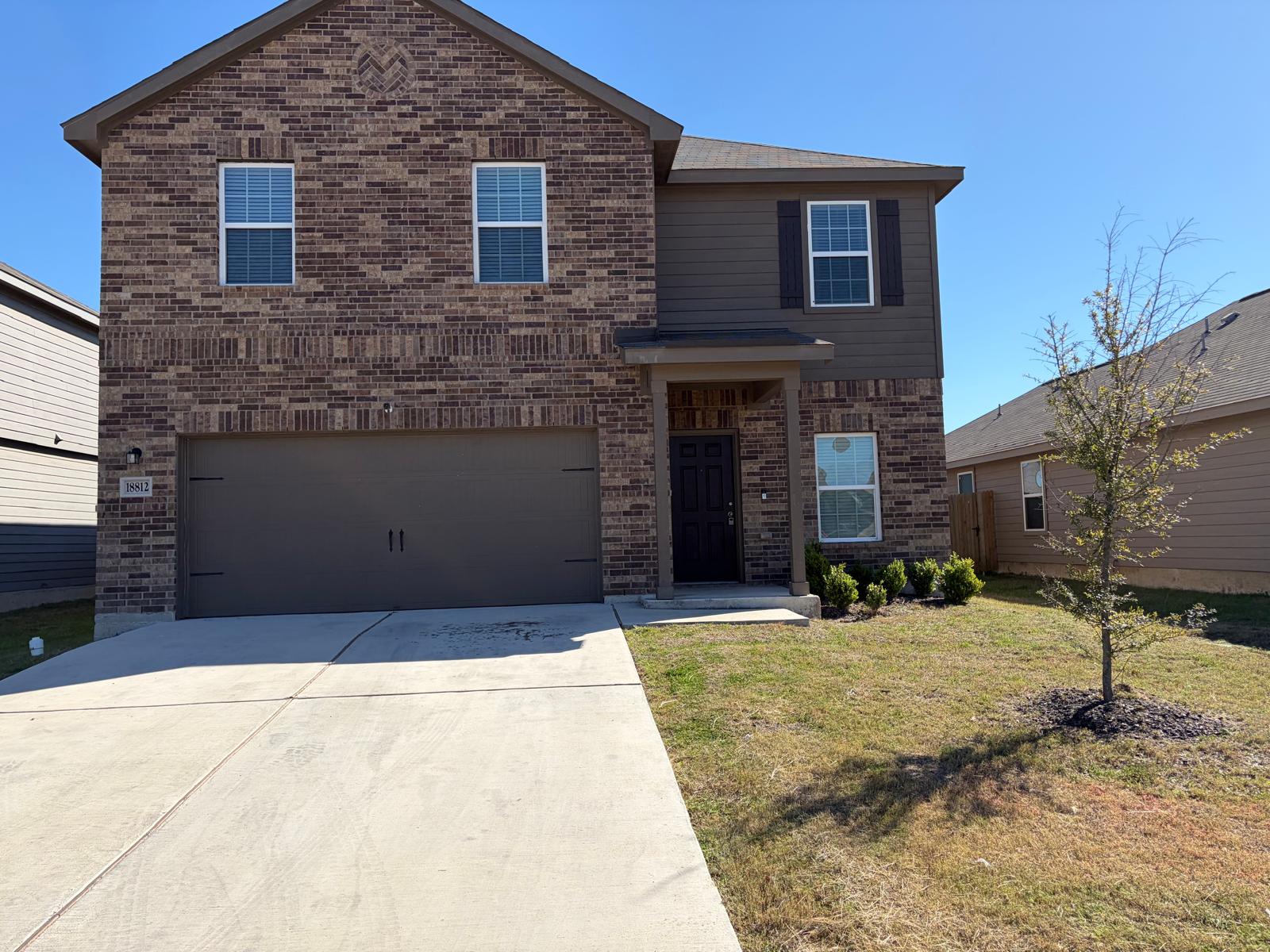 18812 Speculator Lane Elgin, TX 78621 - Photo 3 of 24 Traditional-style house featuring brick siding, driveway, a front yard, and an attached garage
