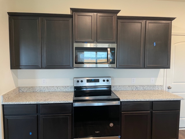 18812 Speculator Lane Elgin, TX 78621 - Photo 9 of 24 Kitchen with stainless steel appliances, light stone counters, and dark brown cabinetry