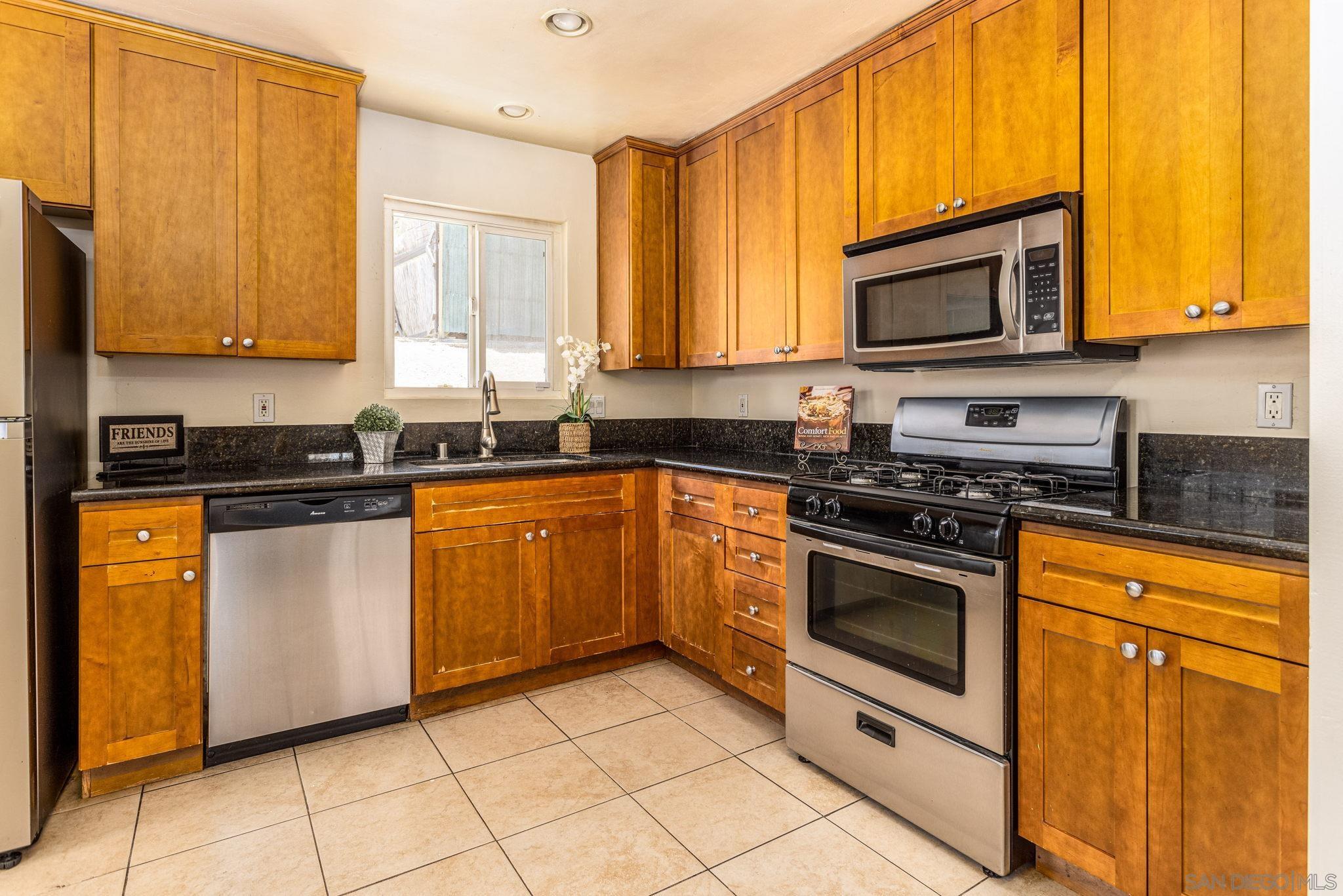 6643 San Miguel Lemon Grove, CA 91945 - Photo 22 of 34 a kitchen with stainless steel appliances granite countertop a stove a sink and a microwave