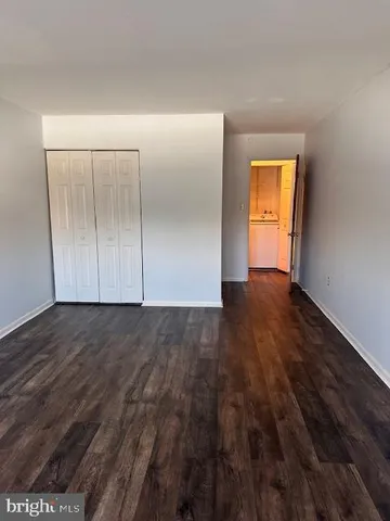 a view of an empty room with wooden floor and closet