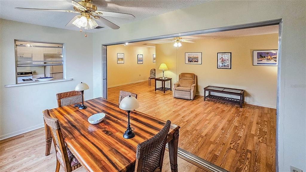5660 80th Street North, Unit A303 St. Petersburg, FL 33709 - Photo 11 of 72 a dining room with wooden floor a chandelier fan a wooden table and chairs