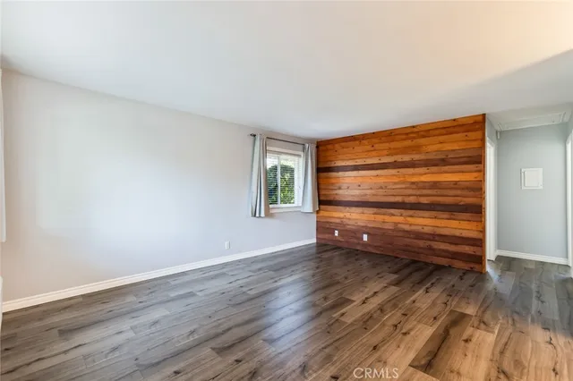 a bedroom with a bed dresser and wooden floor