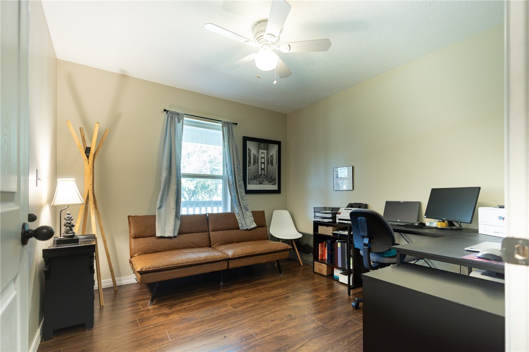 437 Gip Annie Road West Harrison, AR 72601 - Photo 12 of 21 Bright, multi-functional living space featuring hardwood flooring, a ceiling fan with integrated lighting, large windows with natural light, and built-in desk workspace with ample storage cabinetry