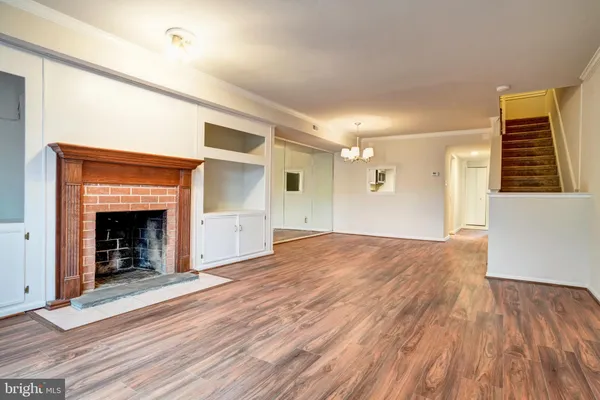 a view of an empty room with wooden floor fireplace and a window