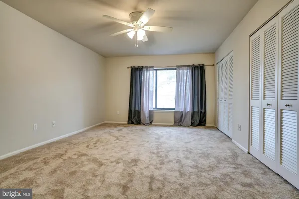 an empty room with windows and fan