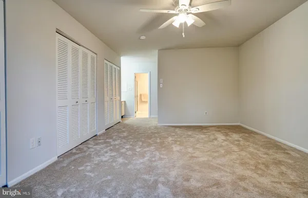 an empty room with a chandelier fan and windows