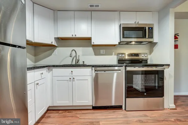 a kitchen with granite countertop white cabinets and stainless steel appliances