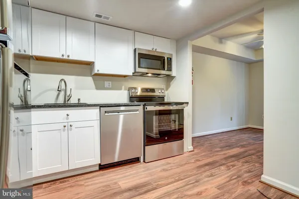 a kitchen with stainless steel appliances granite countertop a stove a sink and a microwave