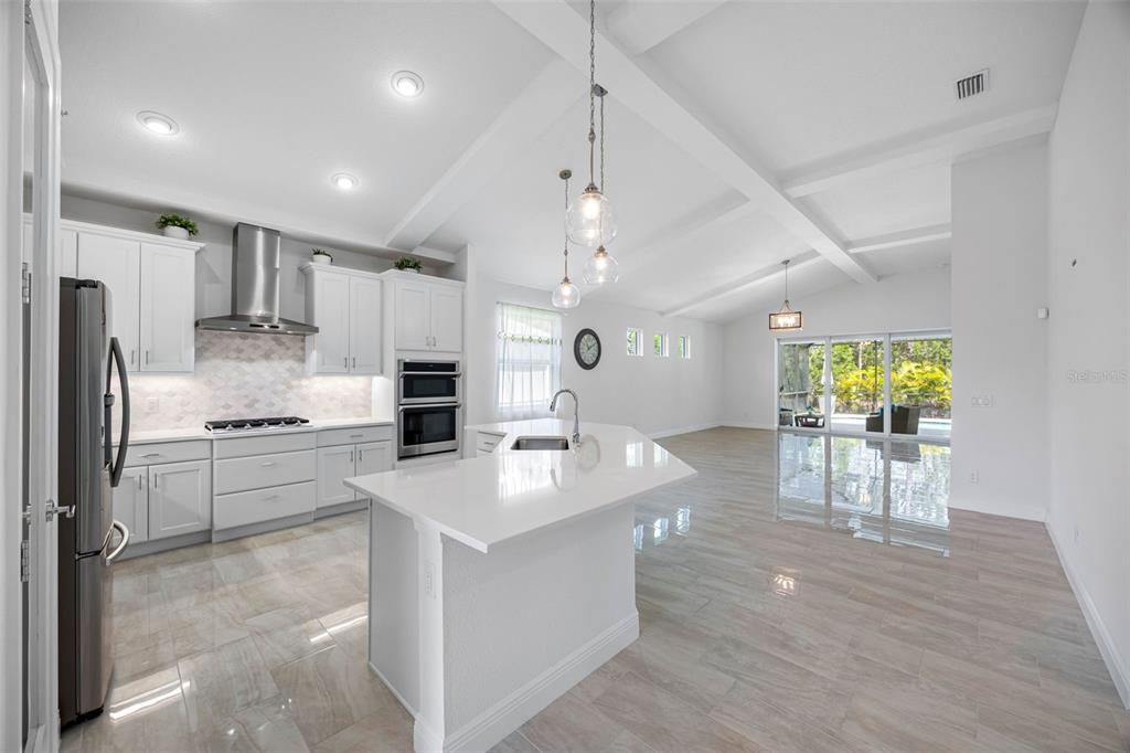 12739 Rainwashed Loop Parrish, FL 34219 - Photo 11 of 45 a large kitchen with kitchen island a island a stove a cabinets and a dining table