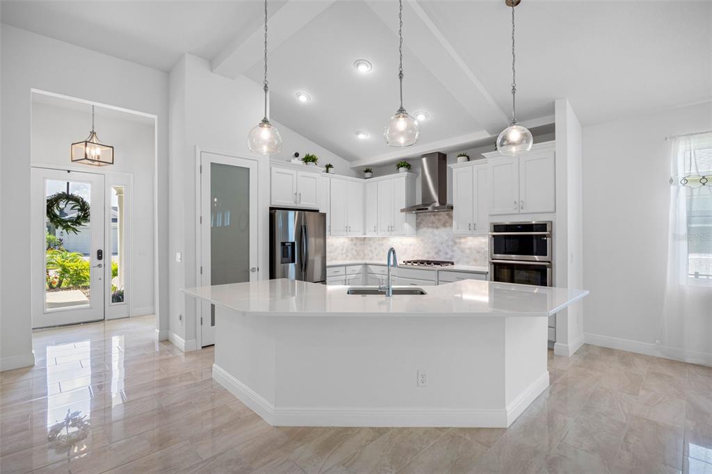 12739 Rainwashed Loop Parrish, FL 34219 - Photo 12 of 45 a large kitchen with stainless steel appliances kitchen island a stove a refrigerator a sink a center island a stove and a window