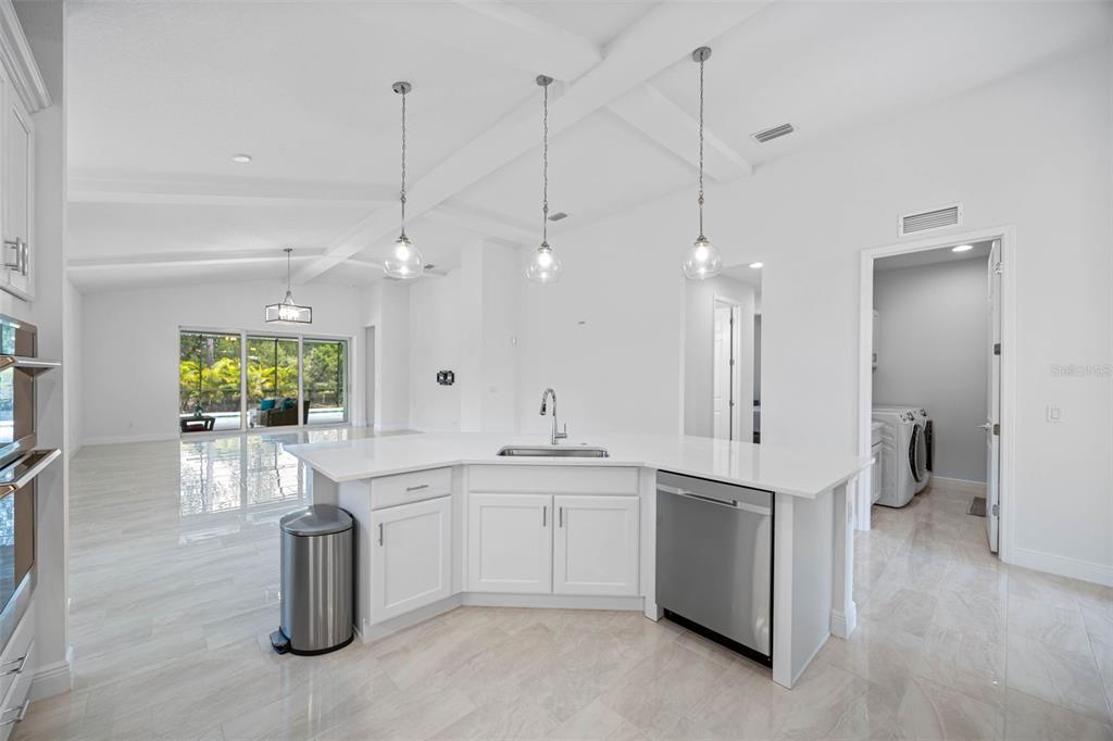 12739 Rainwashed Loop Parrish, FL 34219 - Photo 16 of 45 a large white kitchen with a sink and dishwasher a stove a refrigerator with wooden floor