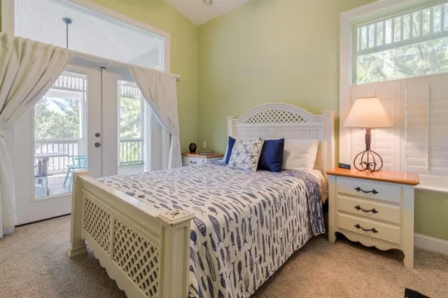 a bedroom with a bed and a lamp on dresser with a large window