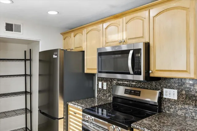 a kitchen with stainless steel appliances granite countertop a refrigerator and a stove top oven