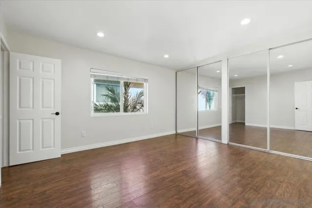a view of an empty room with wooden floor and window