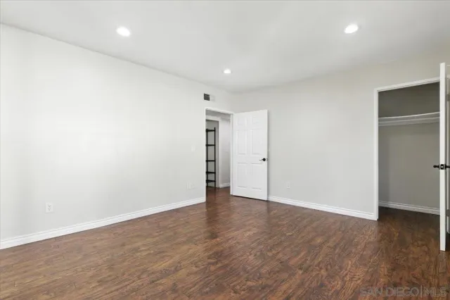a view of an empty room with wooden floor and closet