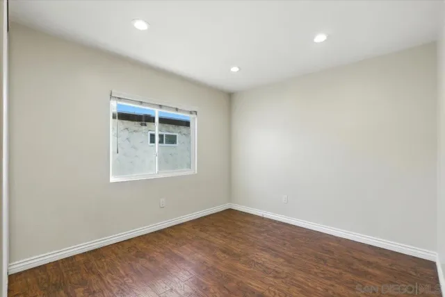 an empty room with wooden floor and a window