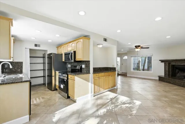 a large kitchen with stainless steel appliances kitchen island granite countertop a refrigerator and a stove top oven