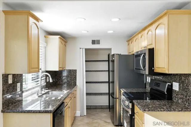 a kitchen with granite countertop a refrigerator stove and sink