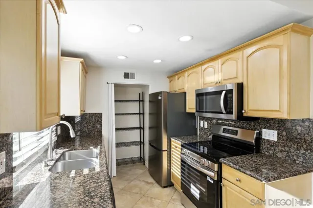 a kitchen with stainless steel appliances granite countertop a stove a sink and a microwave